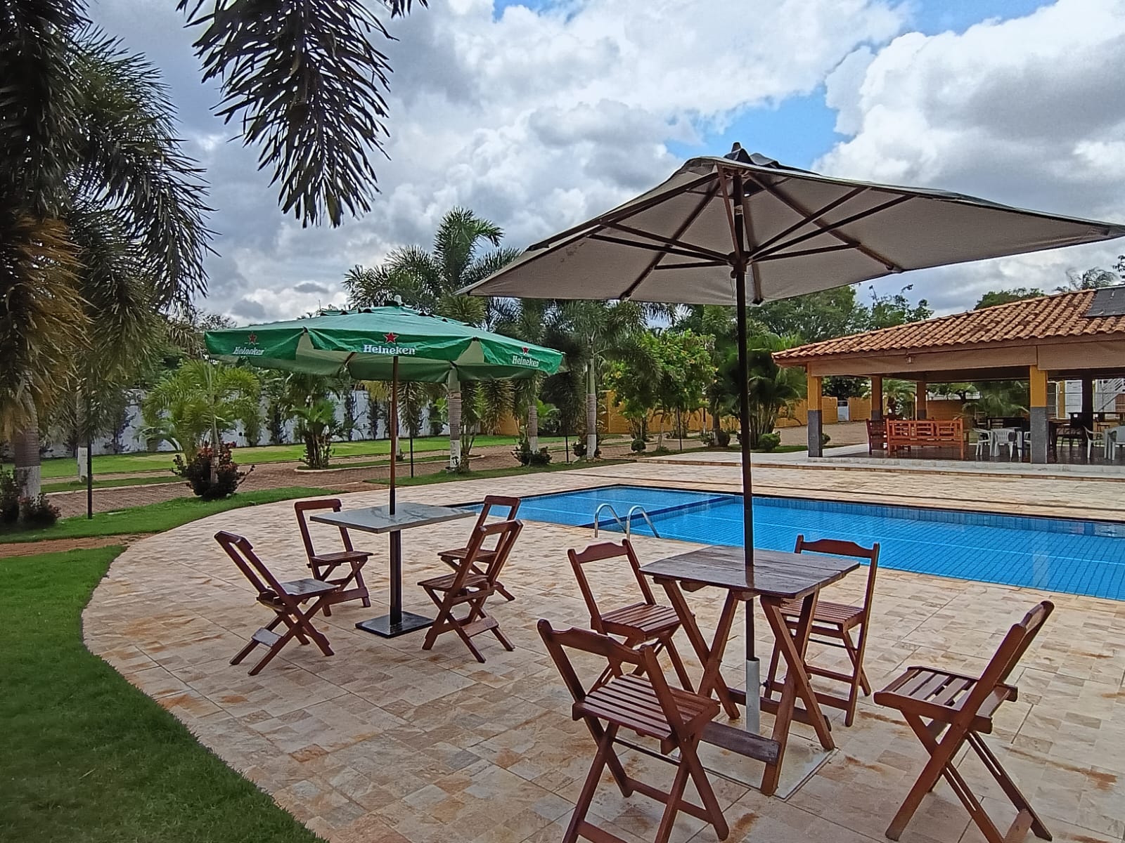 Área da piscina com ombrelones e paisagismo